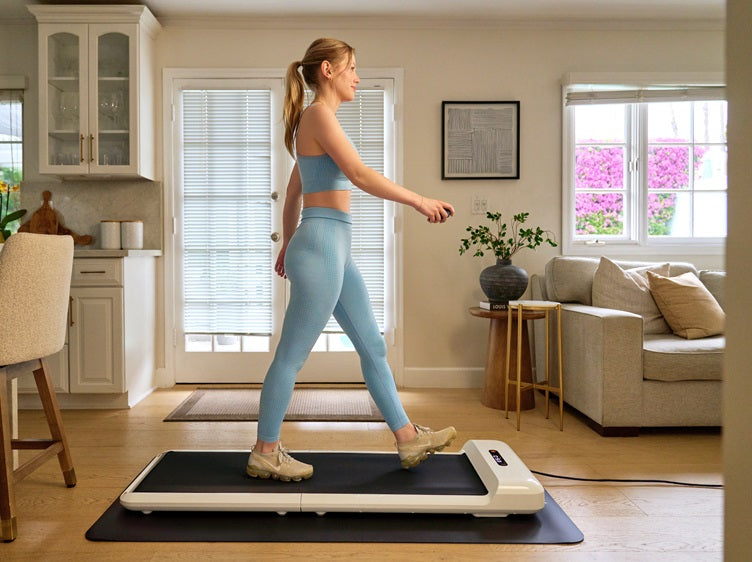 Woman walking indoors on the WalkingPad C2 foldable walking pad in a bright modern living room