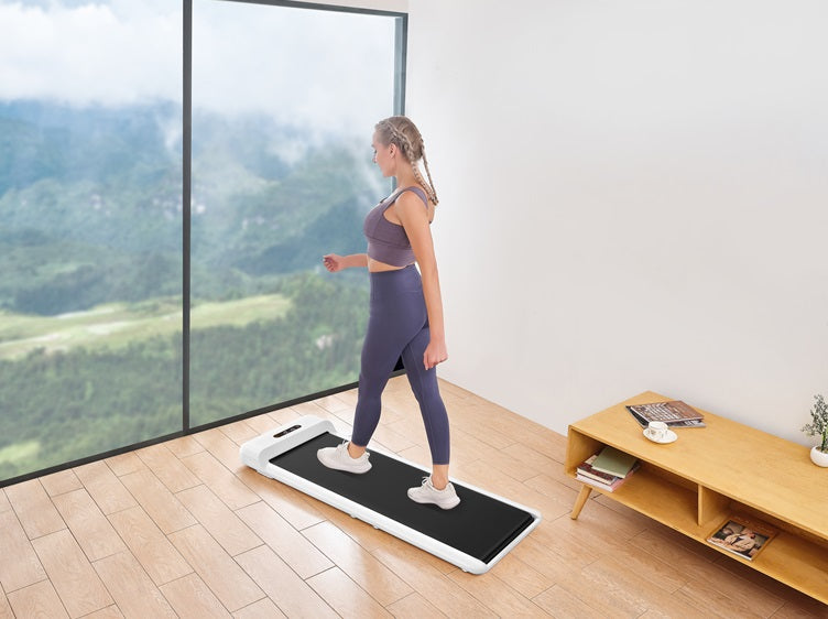 Woman walking on a compact walking pad in a minimalist home with large mountain-view windows