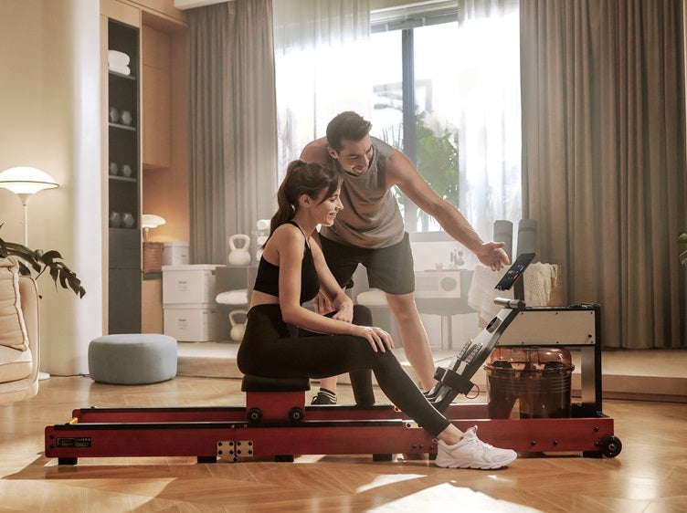 Man guiding a woman using the WalkingPad WM10 hybrid water and magnetic rowing machine at home