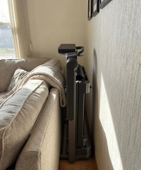 WalkingPad MX10 foldable treadmill stored vertically beside a couch