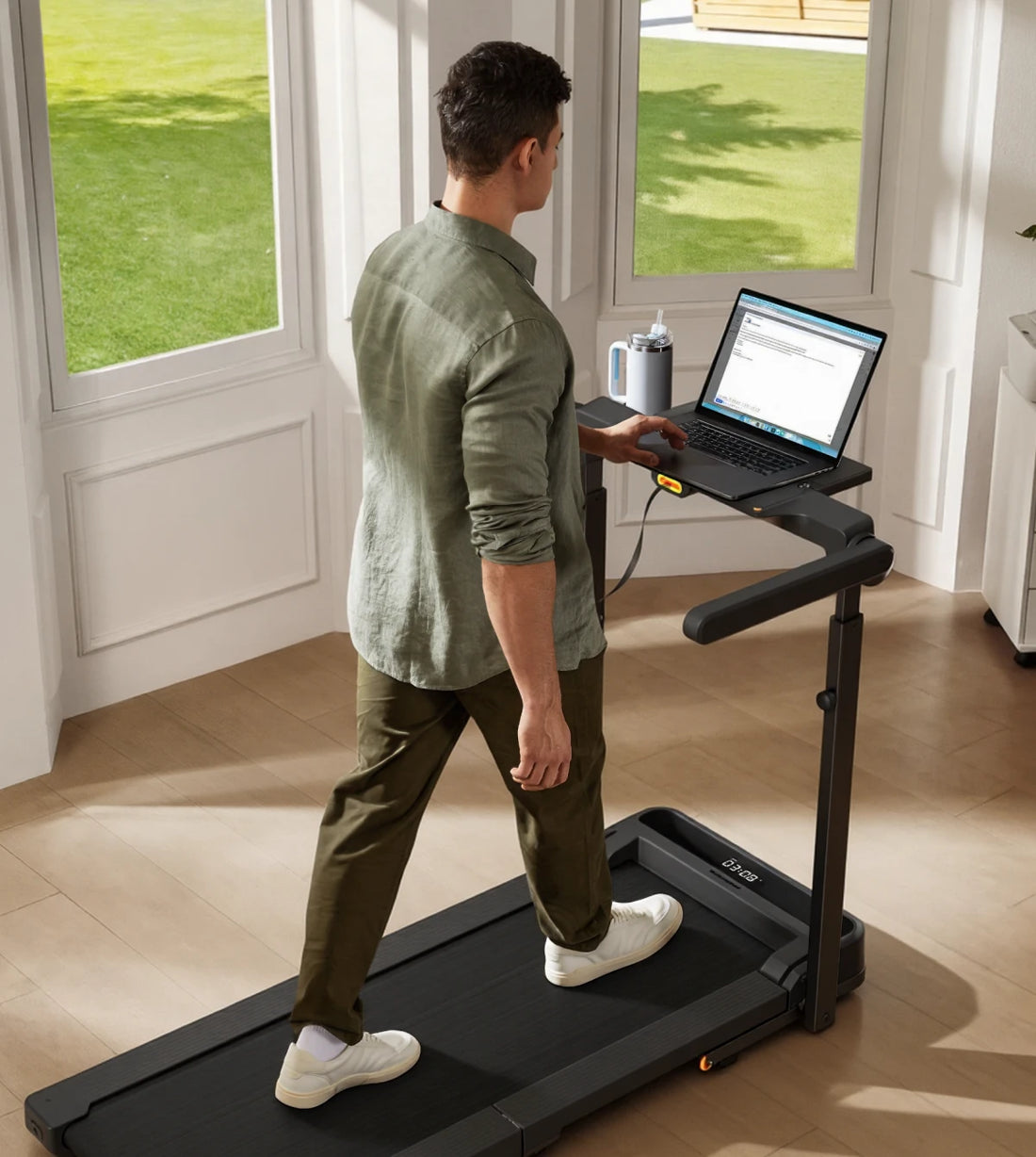 Man walking on the WalkingPad MX10 treadmill while working at a desk