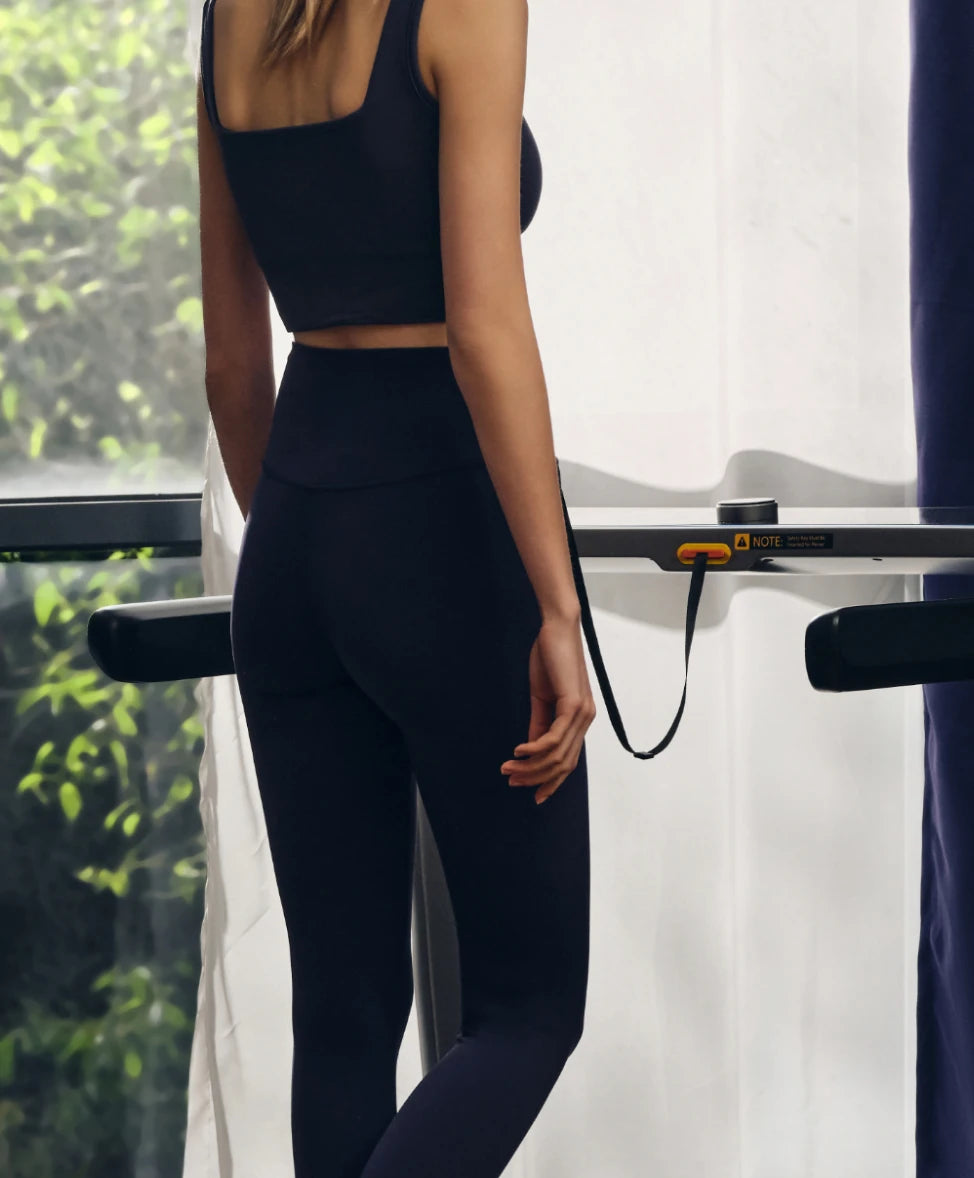 woman walking on treadmill rear view home workout lifestyle scene